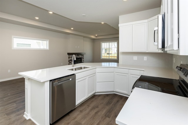 kitchen with a peninsula, dark wood-style floors, stainless steel appliances, and a sink