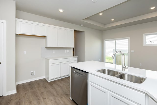 kitchen with white cabinets, stainless steel dishwasher, light countertops, and a sink