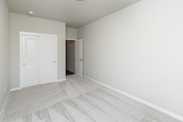 unfurnished bedroom with a closet, carpet flooring, and baseboards