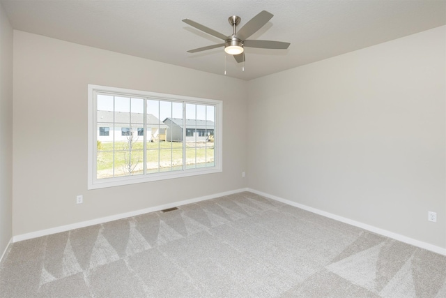 empty room with carpet floors, visible vents, baseboards, and ceiling fan