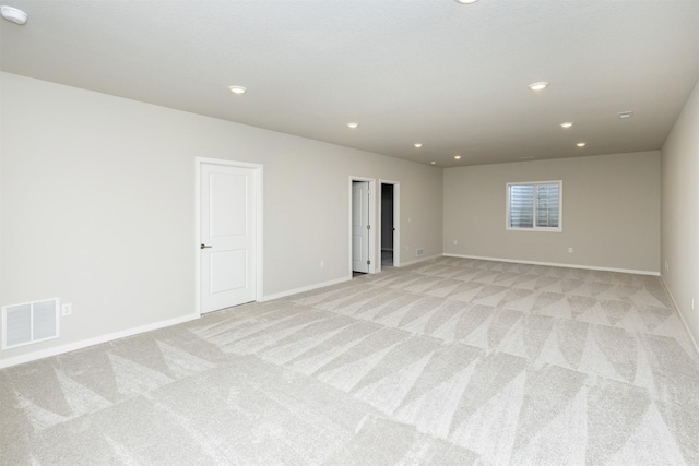 spare room with light colored carpet, baseboards, visible vents, and recessed lighting