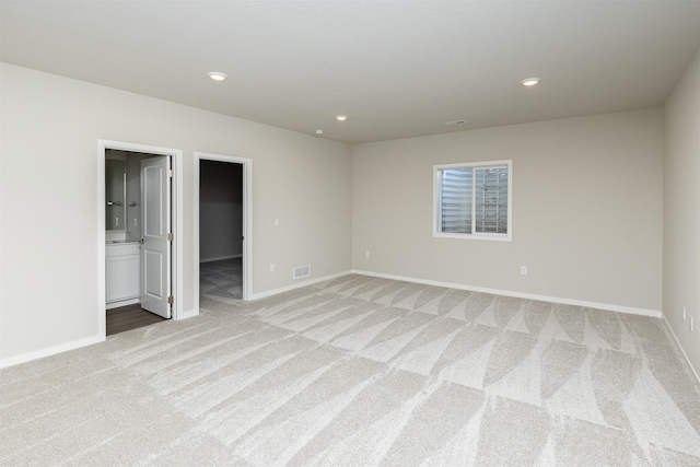 unfurnished bedroom featuring light colored carpet, a spacious closet, baseboards, and visible vents