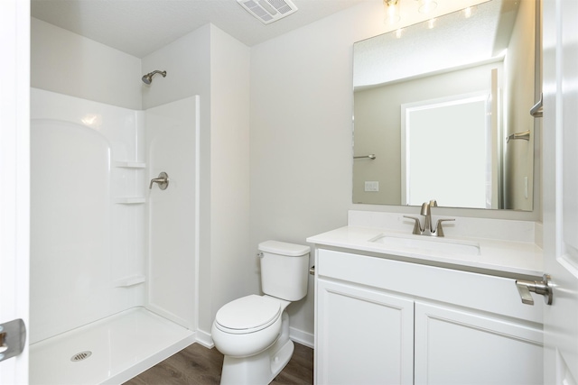 full bath featuring wood finished floors, vanity, a shower, toilet, and visible vents