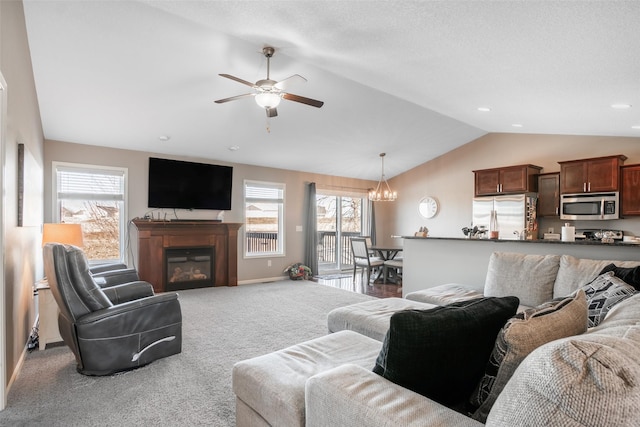 living room with ceiling fan with notable chandelier, carpet floors, and vaulted ceiling