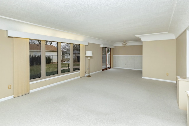 spare room with carpet floors, a textured ceiling, and crown molding