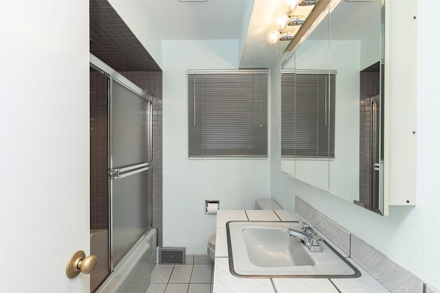 full bathroom featuring toilet, combined bath / shower with glass door, tile patterned floors, and sink