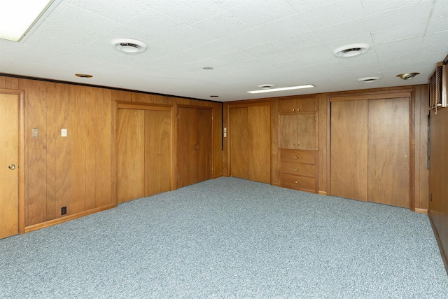 basement featuring light carpet and wooden walls