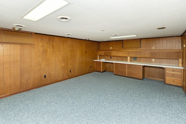 interior space with built in desk, light colored carpet, and wooden walls