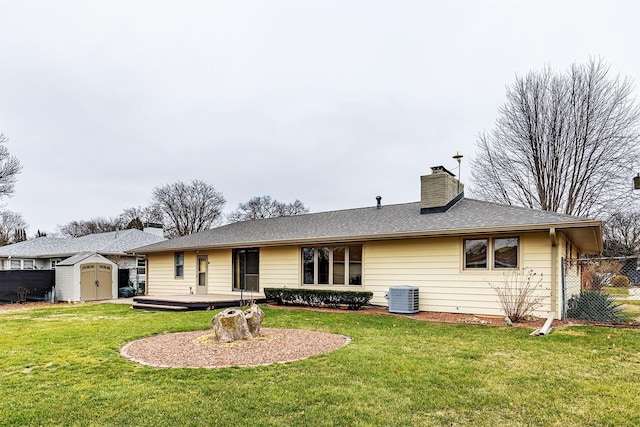 back of property with a deck, a lawn, cooling unit, and a storage shed