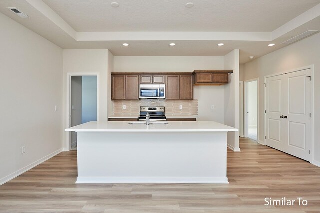 kitchen with a center island with sink, visible vents, stainless steel appliances, and light countertops