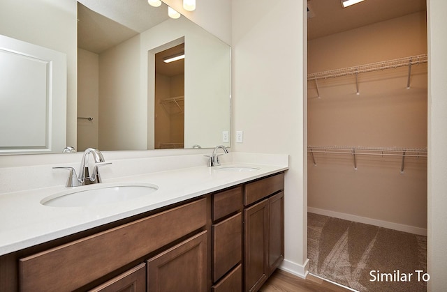 full bath with double vanity, a spacious closet, and a sink