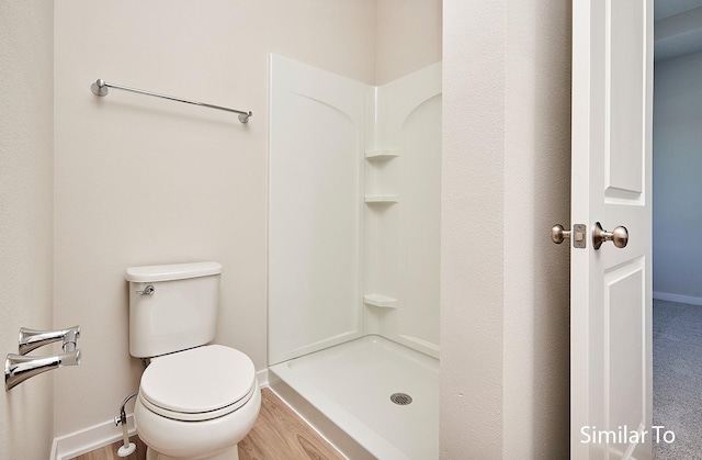 bathroom with a stall shower, baseboards, and toilet