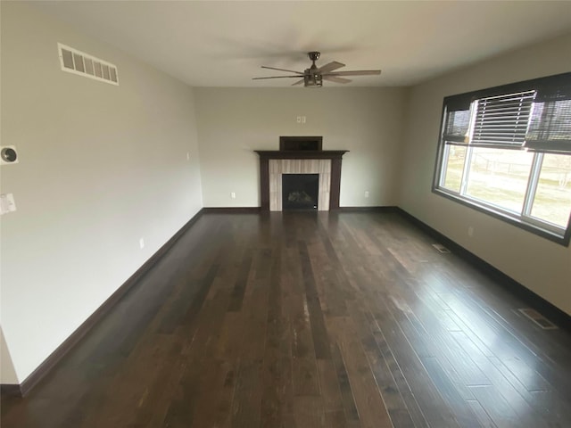 unfurnished living room with a fireplace, ceiling fan, and dark wood-type flooring