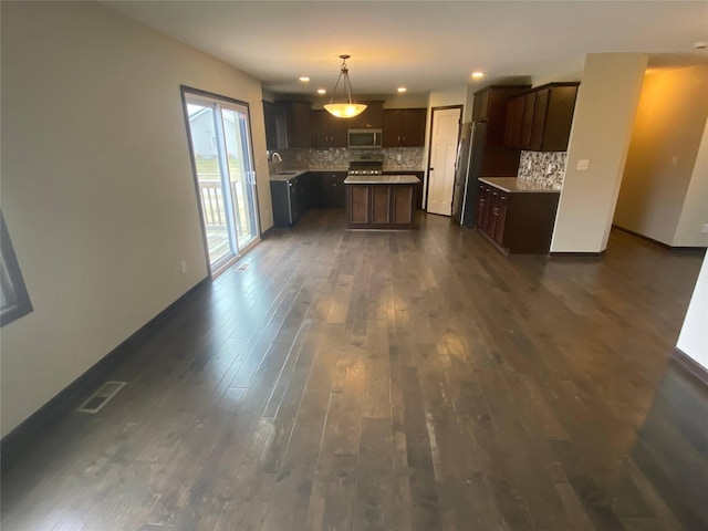 kitchen featuring sink, backsplash, pendant lighting, a kitchen island, and appliances with stainless steel finishes