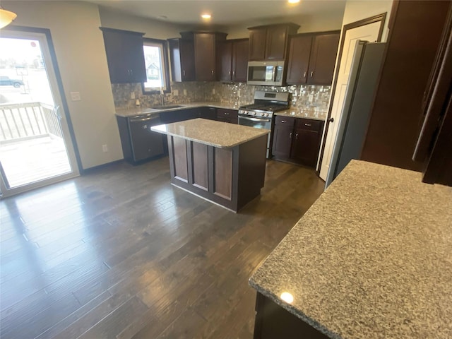 kitchen with a center island, dark wood-type flooring, light stone countertops, dark brown cabinetry, and stainless steel appliances