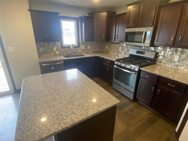 kitchen with appliances with stainless steel finishes, backsplash, light stone counters, and sink