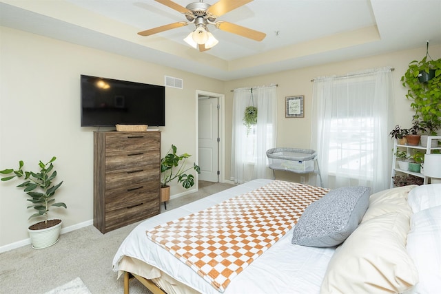 bedroom featuring a raised ceiling, ceiling fan, and light colored carpet