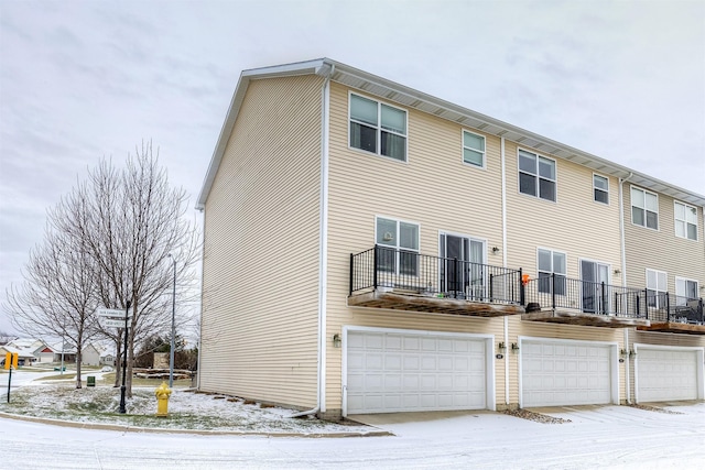 snow covered rear of property with a garage