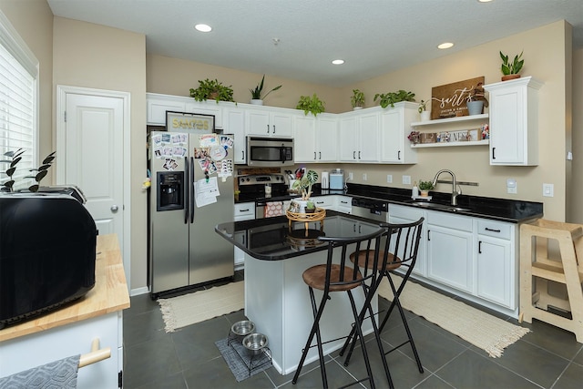 kitchen featuring a kitchen breakfast bar, sink, white cabinetry, and stainless steel appliances