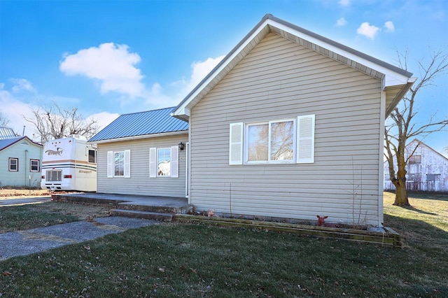 exterior space with metal roof and a lawn