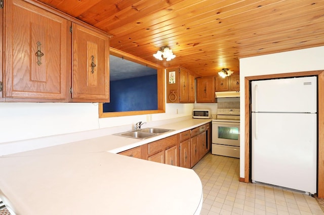 kitchen featuring white appliances, brown cabinetry, light countertops, under cabinet range hood, and a sink