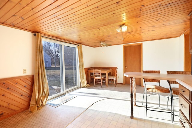 unfurnished dining area with wood ceiling, light colored carpet, wood walls, and a wainscoted wall