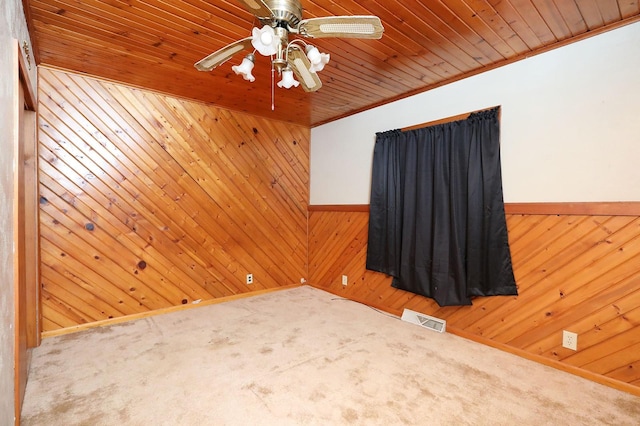 spare room with wood ceiling, wooden walls, visible vents, and carpet flooring