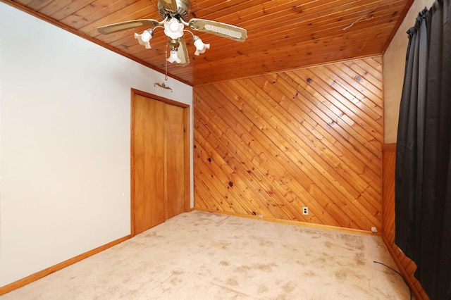 unfurnished room featuring wooden ceiling, carpet flooring, wood walls, and ceiling fan