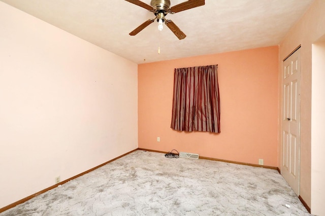 carpeted spare room with ceiling fan, visible vents, and baseboards