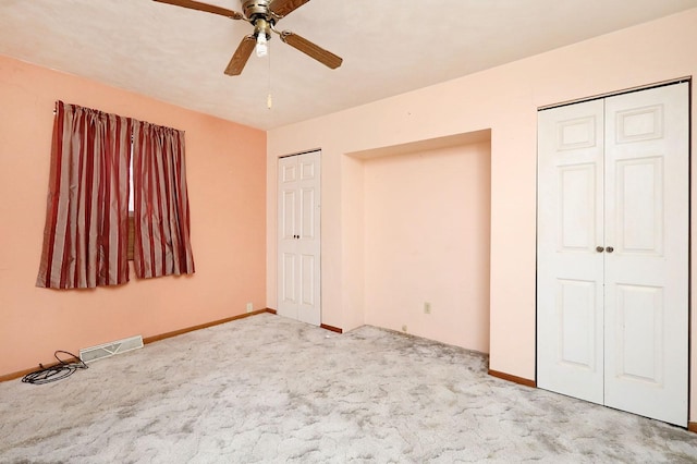 unfurnished bedroom featuring baseboards, carpet, visible vents, and multiple closets