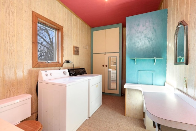 laundry room featuring wooden walls and separate washer and dryer