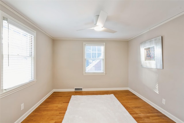 empty room featuring ceiling fan, wood-type flooring, and ornamental molding