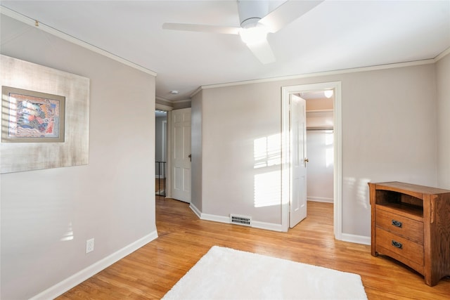 bedroom with ceiling fan, a spacious closet, ornamental molding, and light hardwood / wood-style flooring