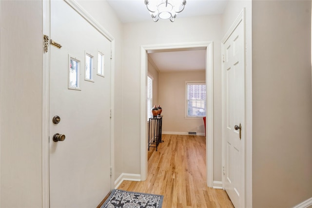 foyer with light hardwood / wood-style floors and a chandelier