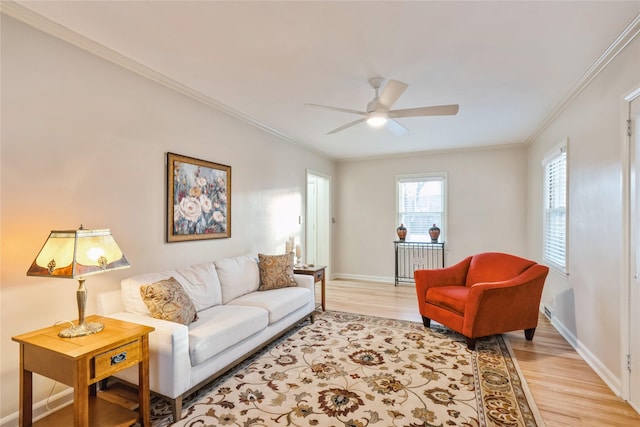 living room featuring light hardwood / wood-style flooring, ceiling fan, and crown molding