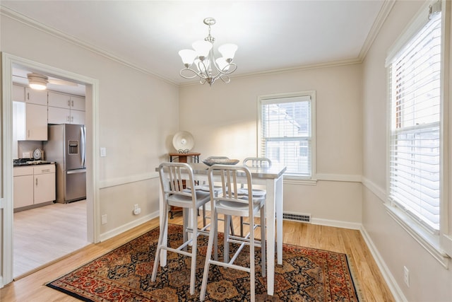 dining area featuring a chandelier, ornamental molding, and light hardwood / wood-style flooring