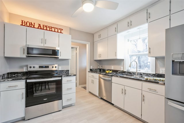 kitchen featuring dark stone countertops, white cabinetry, sink, and appliances with stainless steel finishes