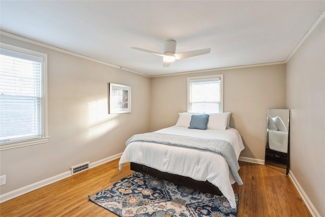 bedroom with hardwood / wood-style floors, ceiling fan, and ornamental molding