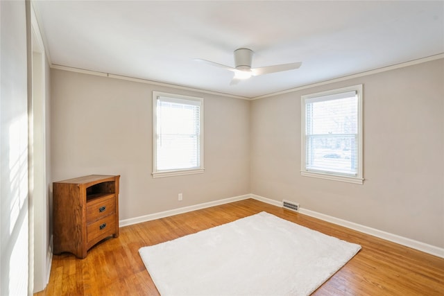 empty room with hardwood / wood-style floors, plenty of natural light, and ornamental molding