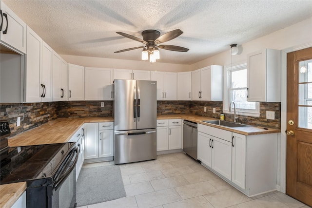 kitchen featuring stainless steel appliances, ceiling fan, sink, white cabinets, and butcher block counters