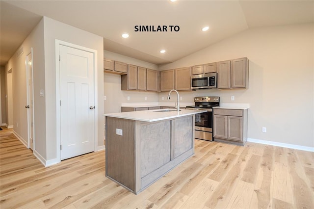 kitchen with stainless steel appliances, vaulted ceiling, sink, light hardwood / wood-style flooring, and an island with sink