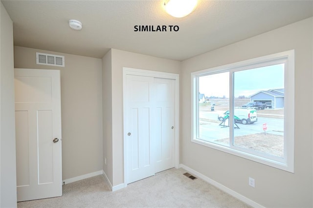 unfurnished bedroom with multiple windows, a closet, and light colored carpet