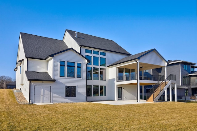 rear view of house featuring stairs, roof with shingles, a lawn, and a patio area