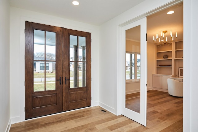 entryway featuring baseboards, french doors, light wood-style flooring, and recessed lighting