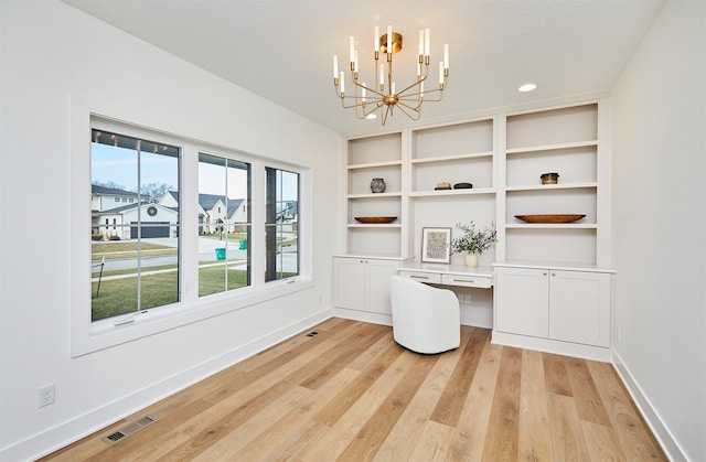 unfurnished office featuring a notable chandelier, visible vents, baseboards, built in study area, and light wood finished floors