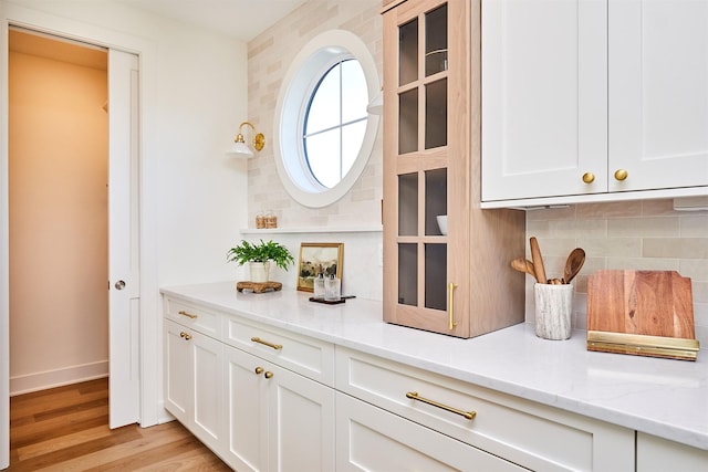 bar with baseboards, light wood-style floors, and decorative backsplash