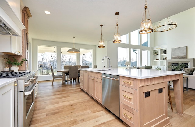 kitchen featuring stainless steel appliances, premium range hood, open floor plan, light countertops, and light wood-type flooring