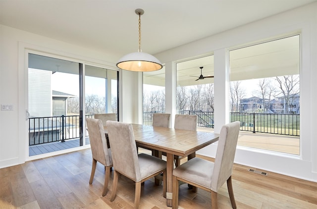 dining room featuring a ceiling fan, visible vents, baseboards, and wood finished floors