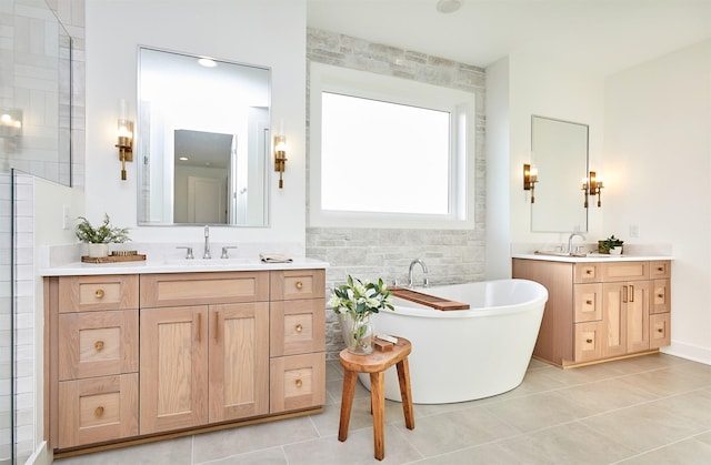 bathroom with a freestanding tub, two vanities, a sink, and tile patterned floors