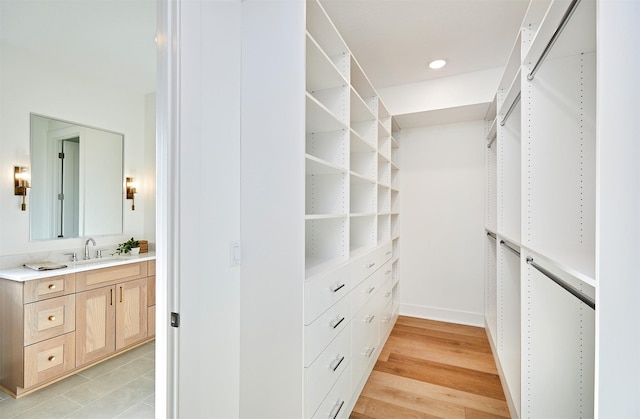 spacious closet featuring light wood finished floors and a sink